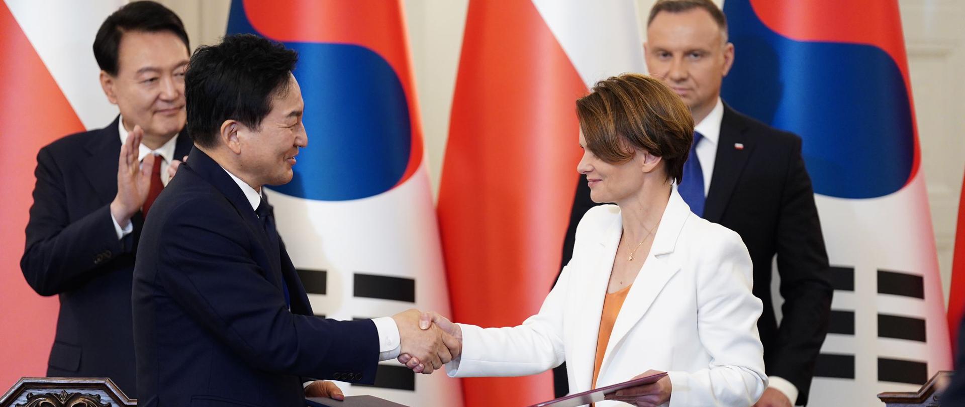 Wiceminister Jadwiga Emilewicz ściska dłoń z południowokoreańskim ministrem ziemi. 