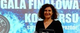 Agnieszka Wabik, zastępca warmińsko-mazurskiego państwowego wojewódzkiego inspektora sanitarnego z nagrodami na tle logo konkursu "Sternik. Cała naprzód". 