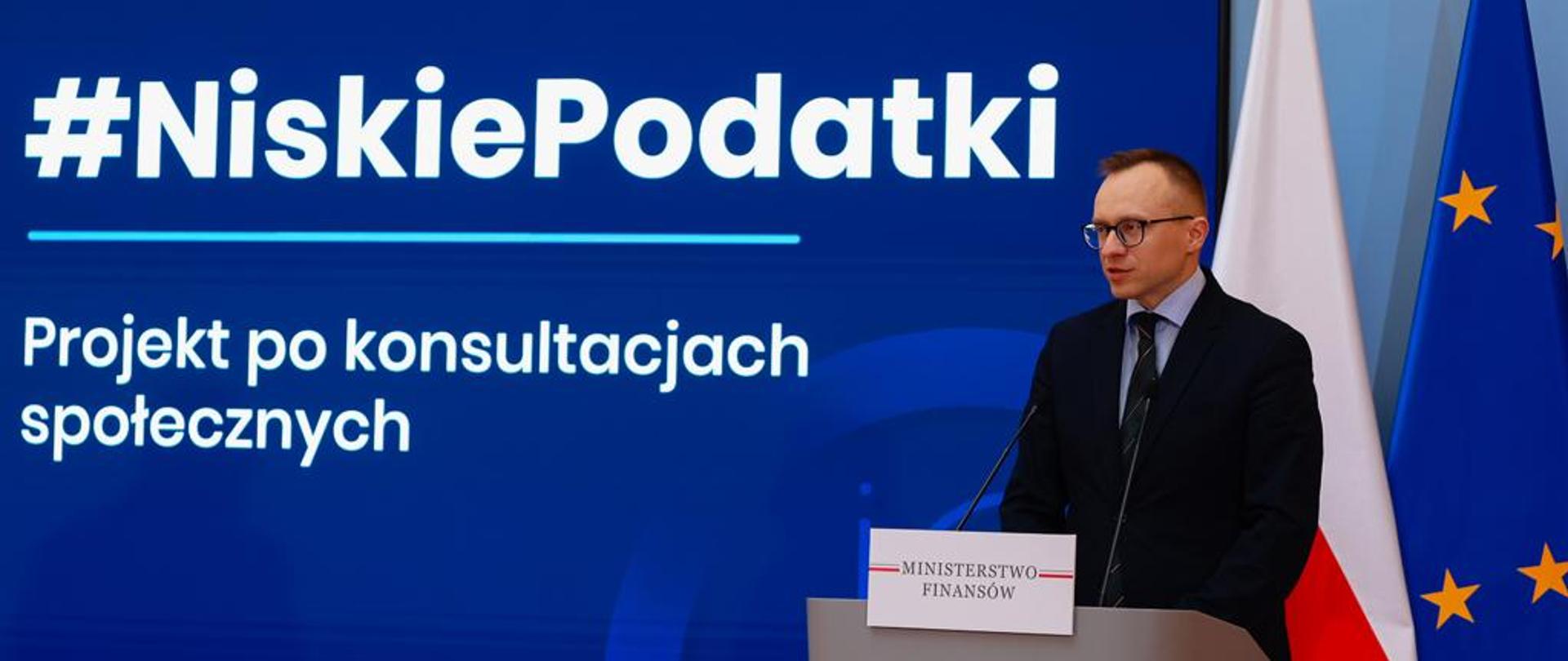 Minister Artur Soboń podczas konferencji na tle banera z napisem Niskie Podatki - projekt po konsultacjach społecznych
