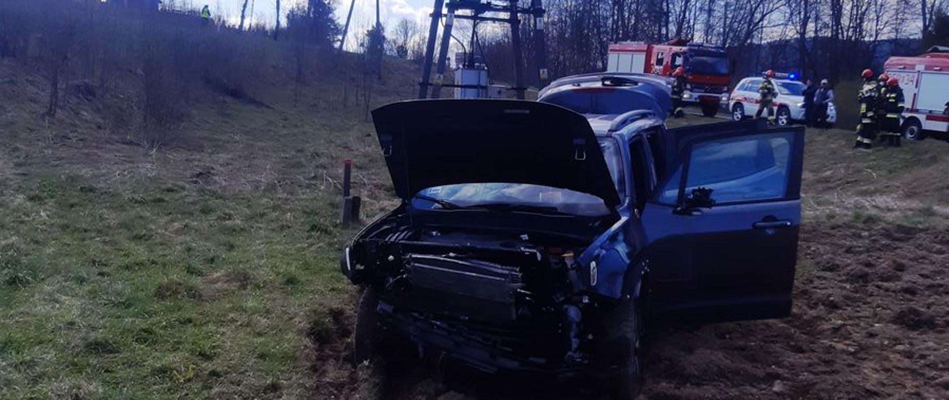 Samochód osobowy stoi na ornym polu. W tle słup energetyczny.