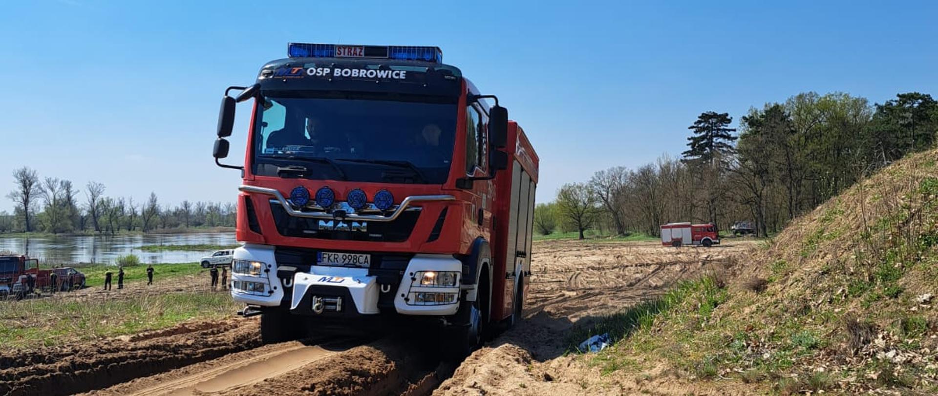 Zdjęcie przedstawia średni samochód ratowniczo - gaśniczy pokonujący podjazd w bardzo dużych koleinach.