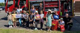 Na zdjęciu dzieci oraz funkcjonariusze Państwowej Straży Pożarnej na tle samochodu strażackiego