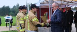 Na zdjęciu starosta wręcza strażakowi puchar za wygraną w zawodach