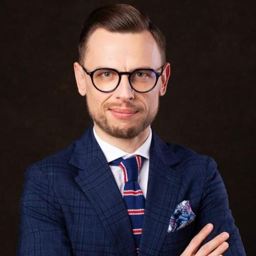 Mężczyzna w okularach i granatowej marynarce.