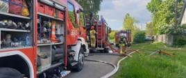 Zdjęcie przedstawia samochody strażackie oraz strażaków podczas pożaru. 