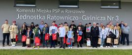 Zdjęcie przedstawia uczestników konkursu trzymających dyplomy, medale oraz puchary, opiekunów oraz organizatorów konkursu podczas pamiątkowej fotografii na zakończenie ogólnopolskiego konkursu wiedzy pożarniczej. Zdjęcie zrobione jest przed budynkiem Jednostki Ratowniczo-Gaśniczej nr 3 w Rzeszowie.