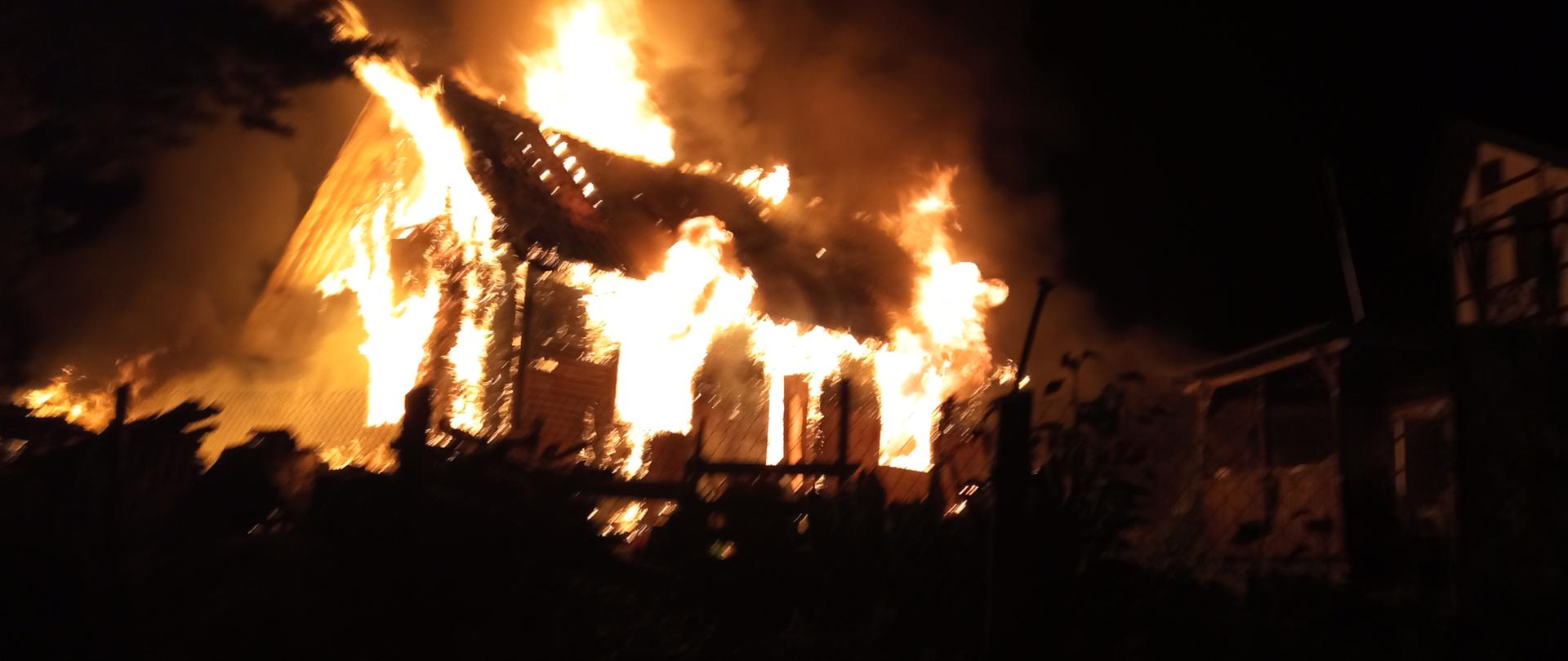 Fotografia przedstawia płonący budynek w porze nocnej.