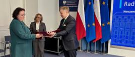 Wiceprzewodnicząca Rady Służby Publicznej prof. Jolanta Itrich-Drabarek odbiera akt powołania z rąk min. Jakuba Stefaniaka, sekretarza stanu, Zastępcy Szefa Kancelarii Prezesa Rady Ministrów; w tle flagi Polski i Unii Europejskiej