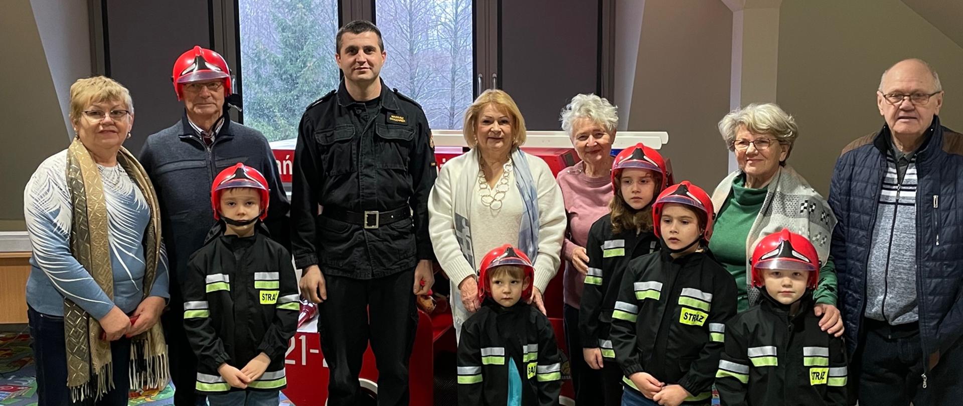 Na zdjęciu strażak wraz z seniorami i wnukami na sali ognik. 