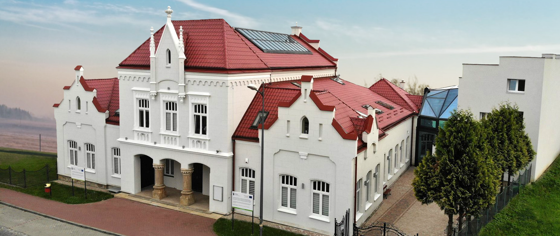 biały obiekt architektoniczny z dwiema kolumnami i zdobionym gzymsem, pokryty czerwonym zadaszeniem, obecna siedziba Państwowej Szkoły Muzycznej I i II stopnia w MIelcu