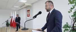 Minister Grzegorz Puda stoi przy mównicy i przemawia do mikrofonu