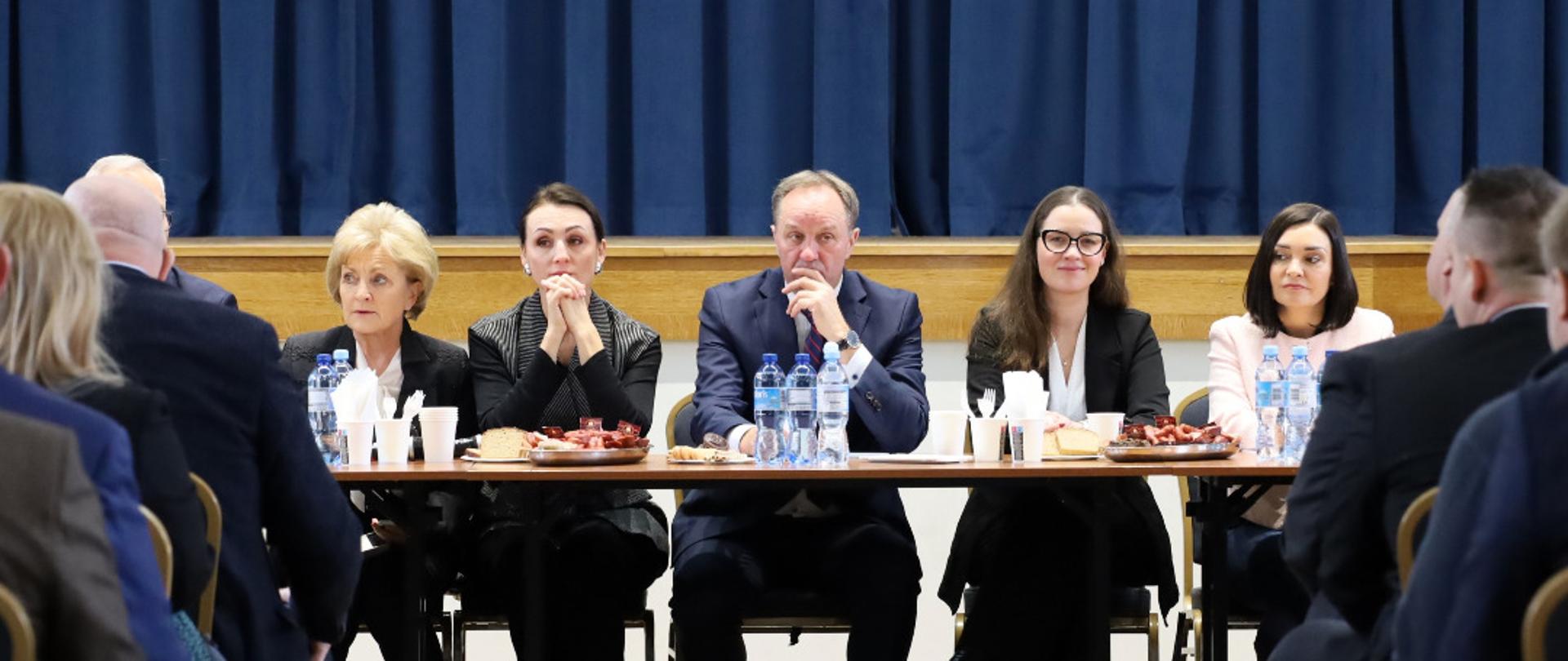 kilka osób siedzi przy stole i rozmawia