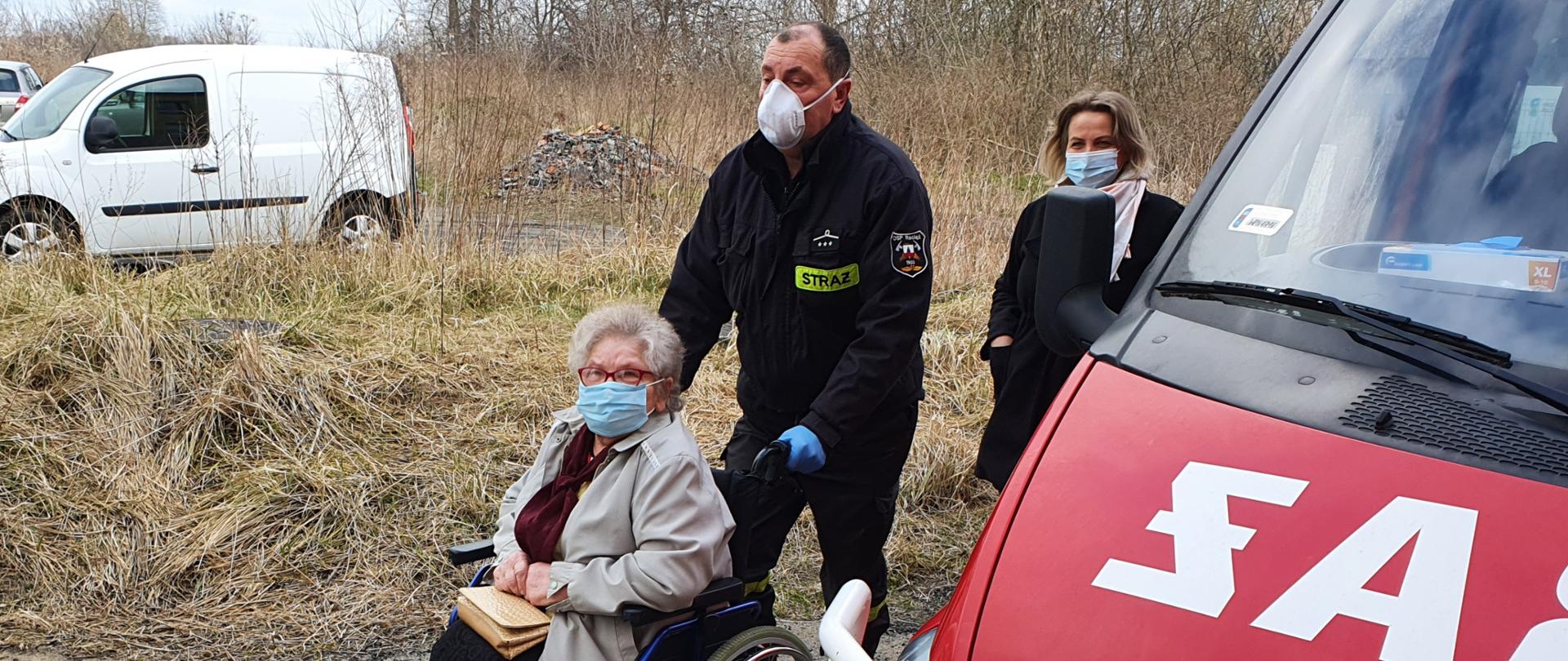 Na zdjęciu strażak pomaga osobie starszej na wózku inwalidzkim
