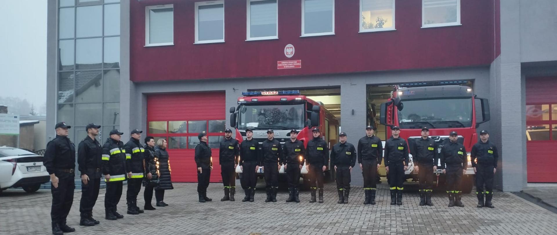 Zdjęcie przedstawia strażaków oddających hołd minutą ciszy za zmarłego strażaka.