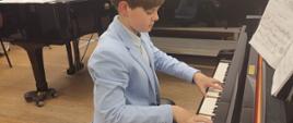 Zdjęcie przedstawia uczestnika Konkursu Twórczości Artystycznej „Echo z dna serca woła mi…” grającego na fortepianie.