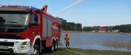 Strażak podaje skuteczny prąd wody z działka samochodu strażackiego.