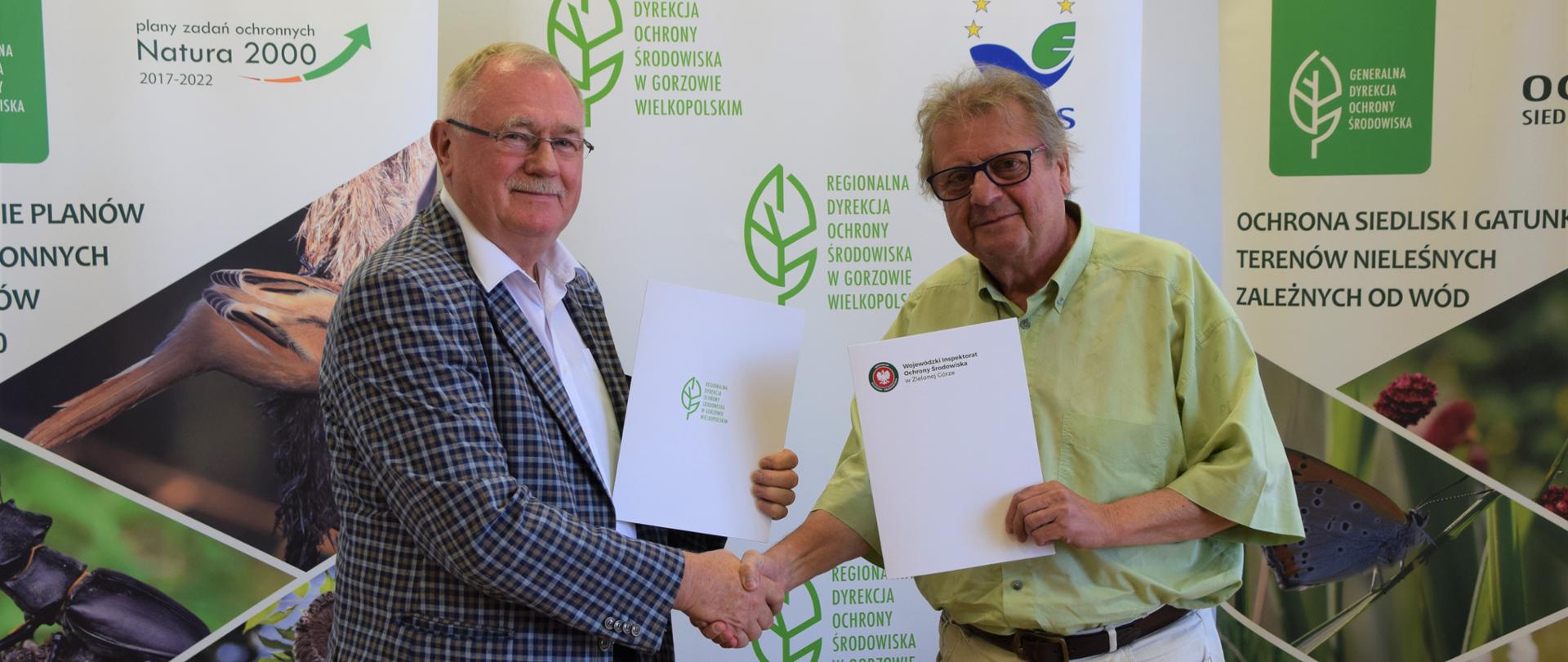 Dwóch mężczyzn pozuje do zdjęcia, ściskając sobie dłonie.