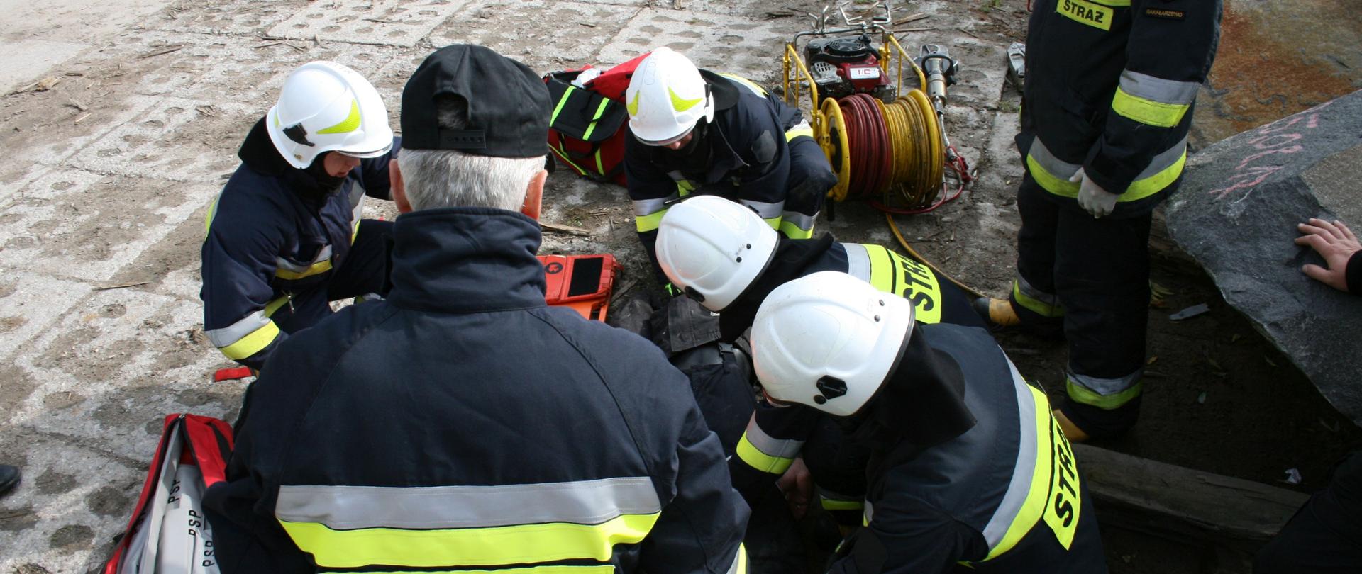 Zdjęcie przedstawia strażaków udzielających pierwszej pomocy