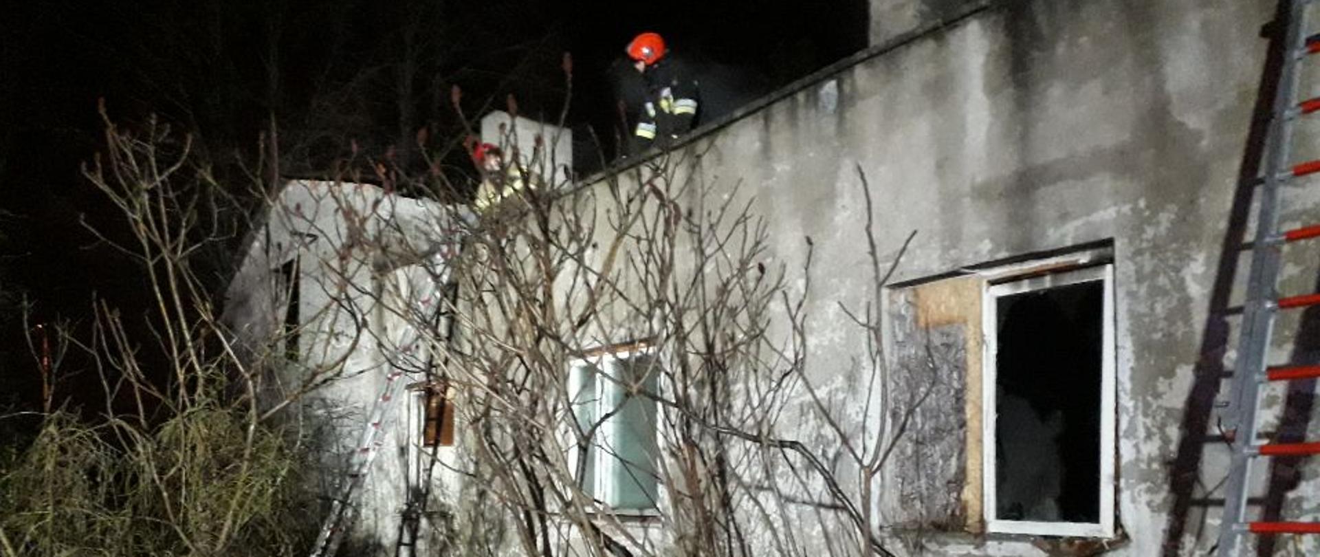 Na zdjęciu widać budynek parterowy, w którym doszło do pożaru oraz strażaków pracujących na dachu.