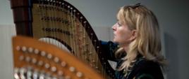 zdjęcie przedstawia nauczyciela gry na harfie przy instrumencie zwracającego się do wykładowcy