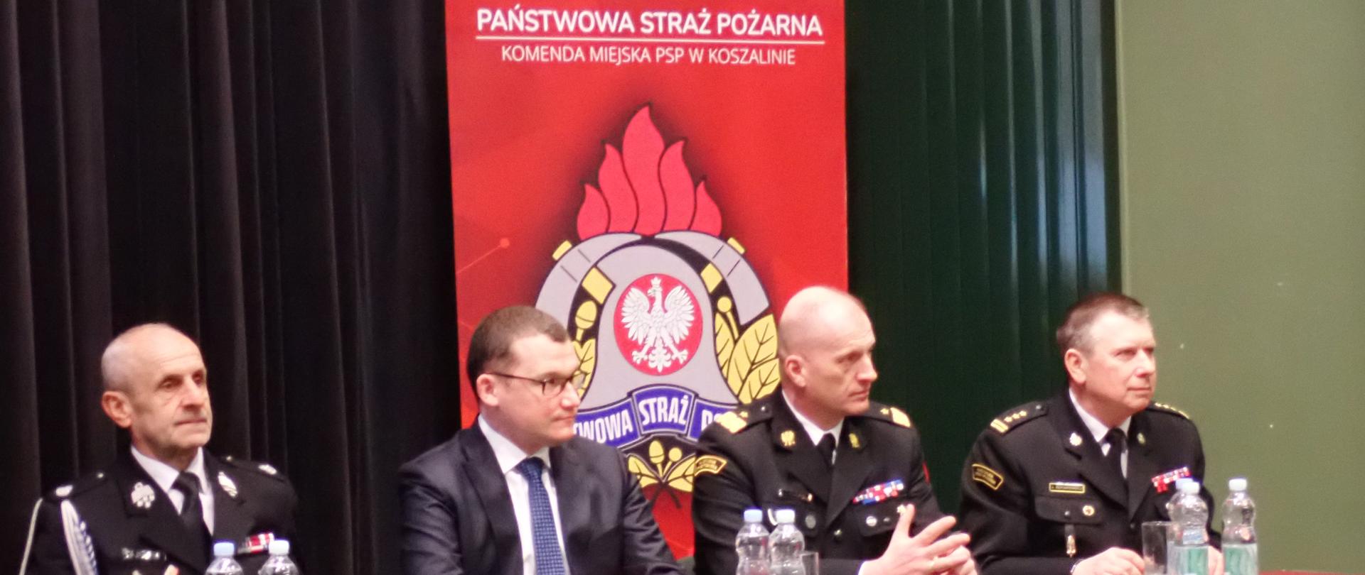Narada podsumowująca działalność KM PSP w Koszalinie za rok 2022. Stół prezydialny z gośćmi.