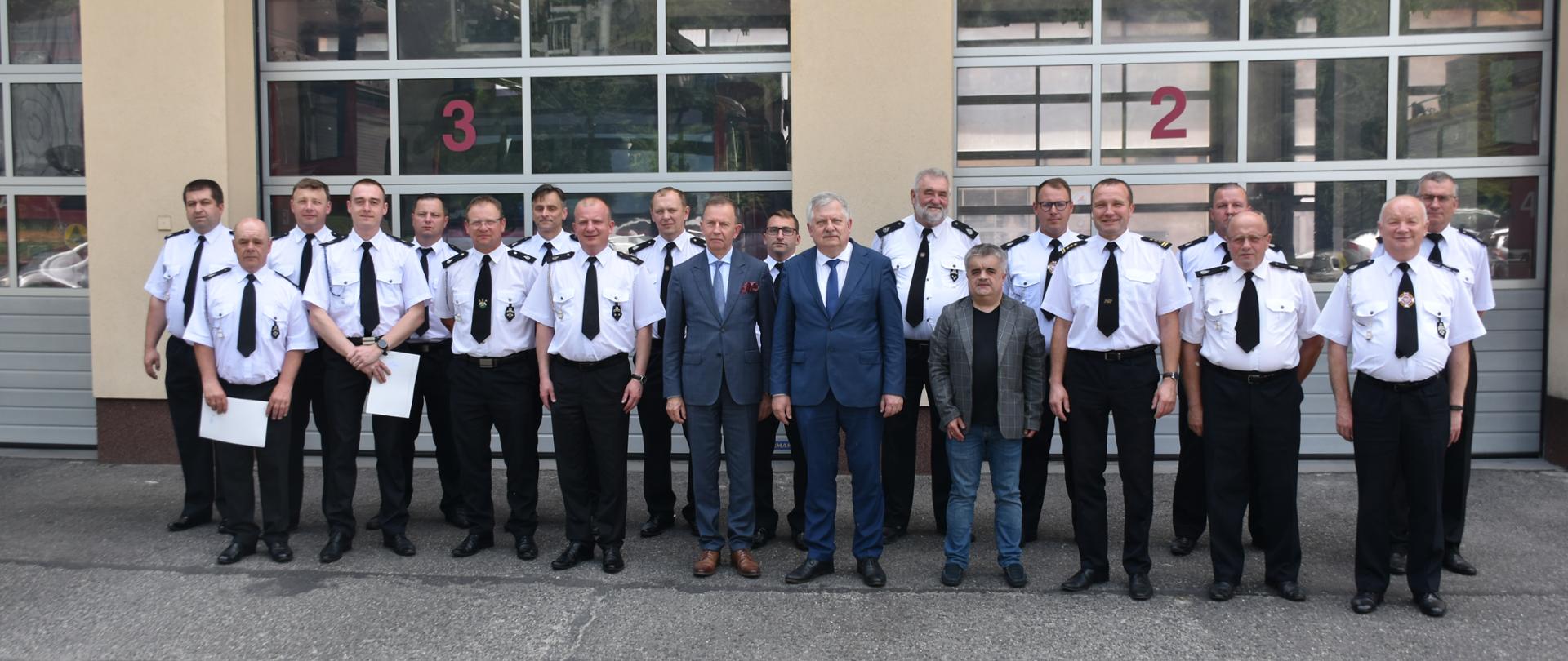 Zdjęcie przedstawia plac zewnętrzny Komendy Powiatowej. Na pierwszym planie przed budynkiem Komendy stoją przedstawiciele jednostek Ochotniczych Straży Pożarnych z powiatu łańcuckiego, Komendant Powiatowy Państwowej Straży Pożarnej w Łańcucie starszy brygadier Bogusław Golenia, Poseł na Sejm Kazimierz Gołojuch, zastępca prezesa Wojewódzkiego Funduszu Ochrony Środowiska i Gospodarki Wodnej w Rzeszowie Bogusław Kida.