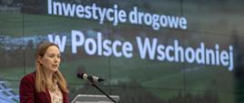 Minister funduszy i polityki regionalnej Katarzyna Pełczyńska-Nałęcz, minister stoi przy mównicy i przemawia do mikrofonu, za jej placami ekran z napisem: "Inwestycje drogowe w Polsce Wschodniej"