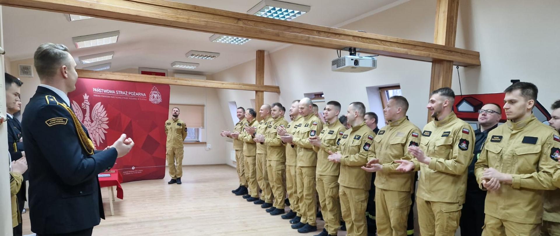 Funkcjonariusze bijący gratulacyjne brawa z okazji przejścia na zaopatrzenie emerytalne