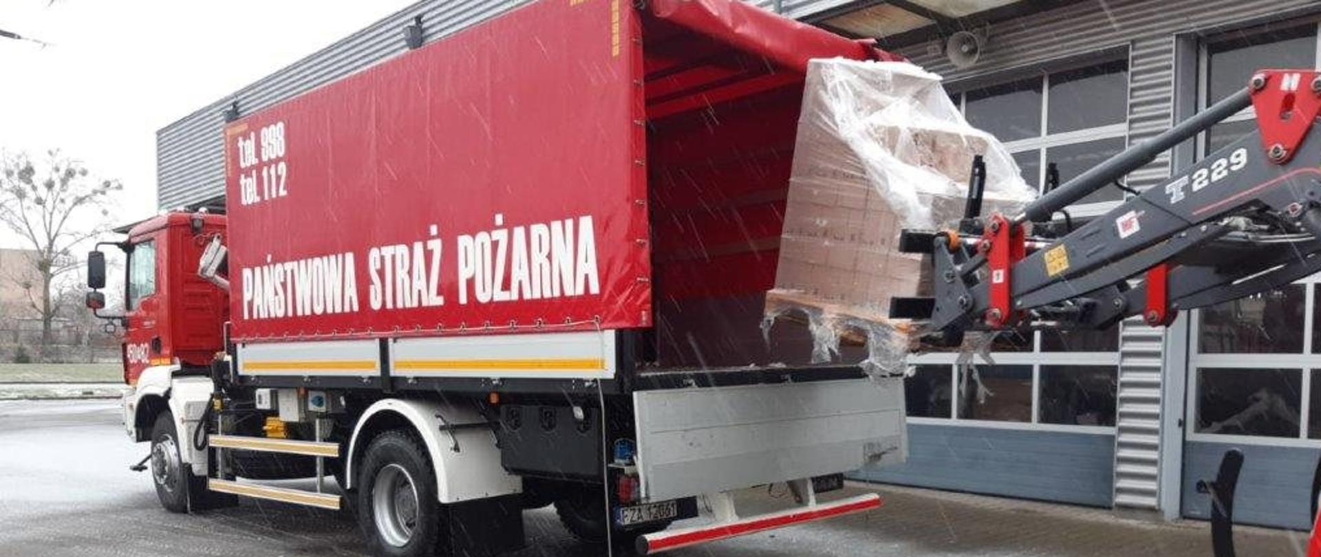 Zdjęcie przedstawia rozładunek płynu do dezynfekcji i maseczek dostarczonych jako wsparcie w walce z koronawirusem z Agencji Rezerw Materiałowych.