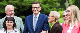 Premier Mateusz Morawiecki spaceruje z seniorami po parku w Żelazowej Woli.