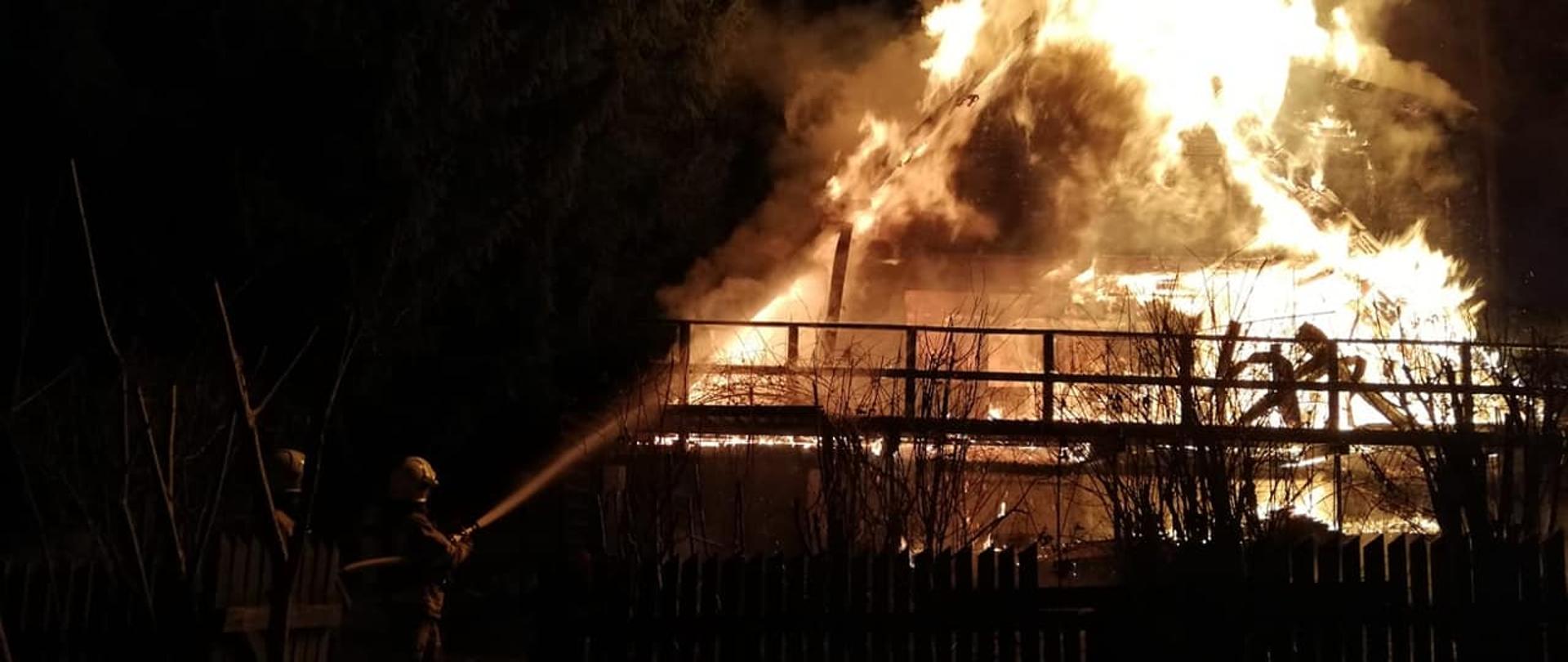 Zdjęcie przedstawia w pełni rozwinięty pożar domku letniskowego w miejscowości Narty