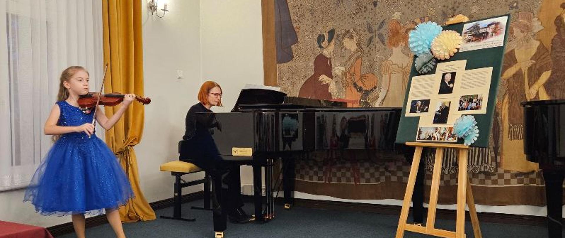 Uczennica ZPSM gra na skrzypcach, akompaniuje przy fortepianie nauczyciel, obok stoi sztaluga z obrazkami