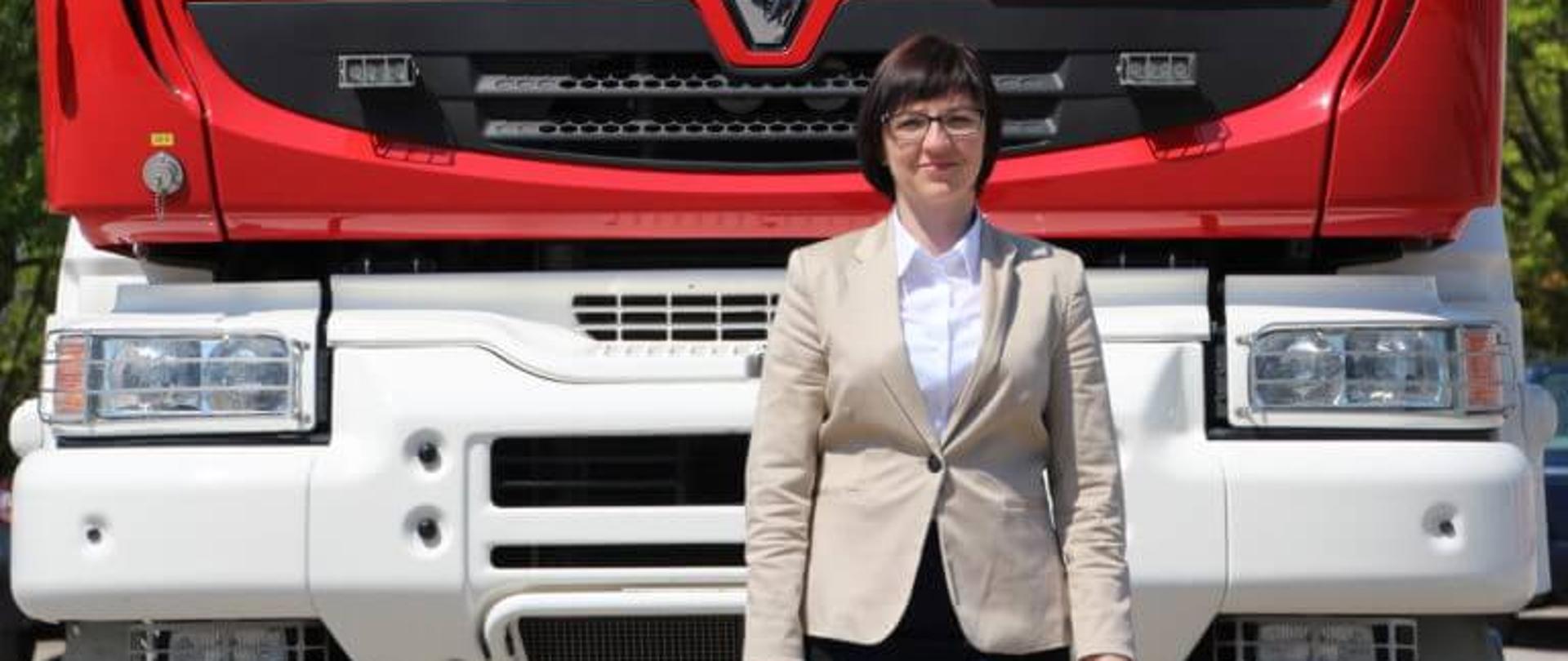 Na zdjęciu stoi Pani z działu księgowości pozujący do zdjęcia przed wozem bojowym.