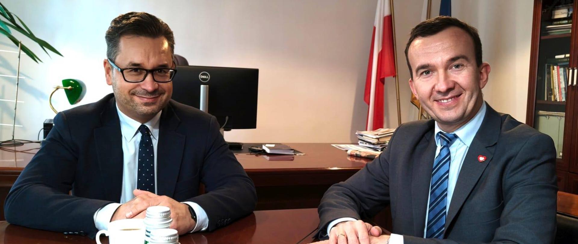 Dwóch mężczyzn siedzi przy biurku