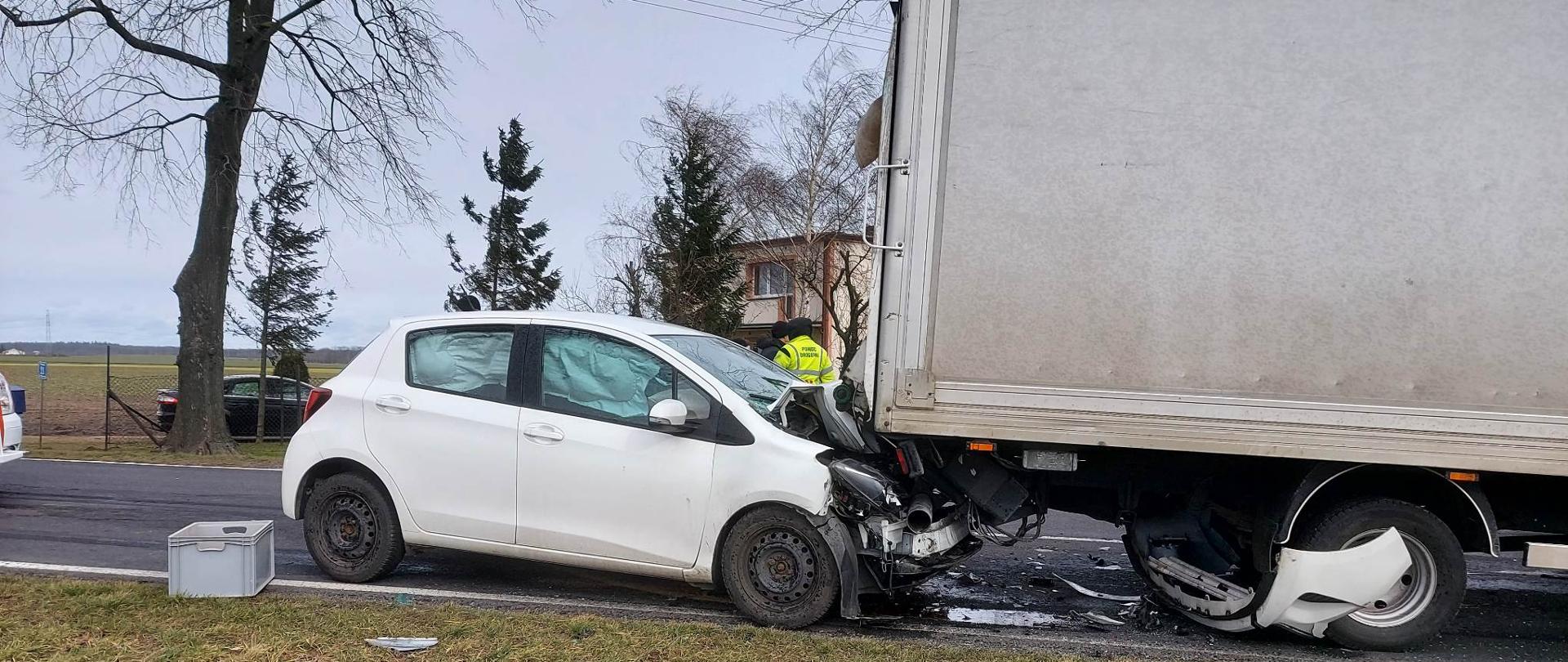 Widać uszkodzony biały samochód od strony pasażera, który uderzył w tył innego pojazd