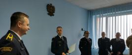 Komendant Powiatowy PSP odczytuje meldunek odchodzącemu na emeryturę strażakowi. Za komendantem stoją dowódcy JRG.