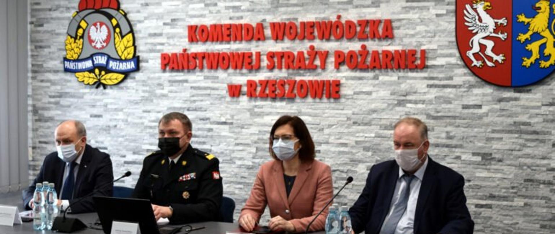 Od lewej, na tle ściany z napisem Komenda Wojewódzka Państwowej Straży Pożarnej w Rzeszowie, przy stole prezydialnym siedzą: poseł na Sejm RP Zbigniew Chmielowiec, komendant wojewódzki PSP nabdryg. Andrzej Babiec, wojewoda podkarpacki Ewa Leniart i wicemarszałek województwa podkarpackiego Piotr Pilch. 