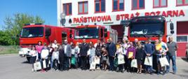 Zdjęcie grupowe wszystkich uczestników na tle garażu i samochodów gaśniczych