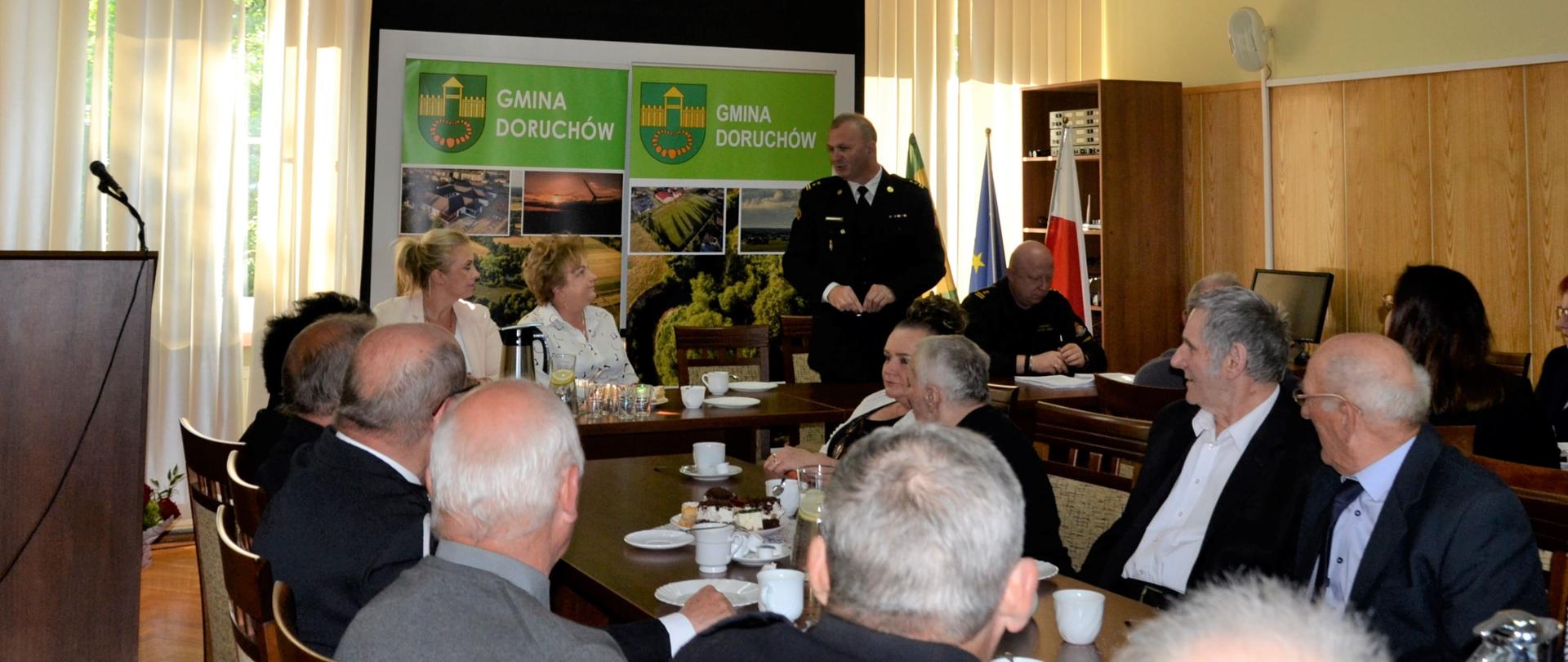 Komendant Powiatowy PSP w Ostrzeszowie Piotr Mazurkiewicz z panią poseł Katarzyną Sójką. Na pierwszym planie siedzą druhowie, którzy otrzymali świadczenia ratownicze.