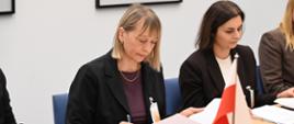 Two women are sitting at the conference table and reading documents
