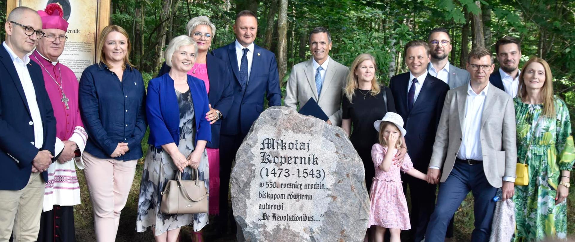 grupa ludzi stoi przy kamieniu 