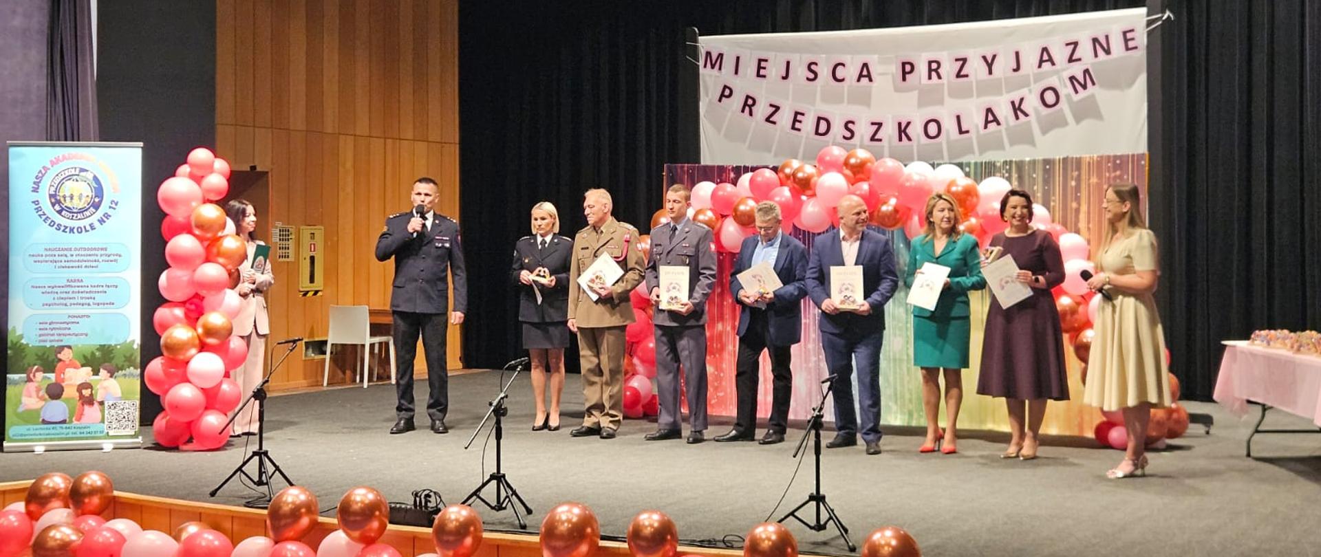 Gala rozdania statuetek „Miejsce Przyjazne Przedszkolakom”. Przedstawiciele służb i instytucji otrzymują statuetki na scenie.