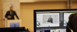 Minister funduszy i polityki regionalnej Grzegorz Puda podczas 5. Forum Akademicko-Gospodarczego, minister stoi przy mikrofonie i przemawia, na pierwszym planie widać ekran komputera na którym jest zdjęcie ministra