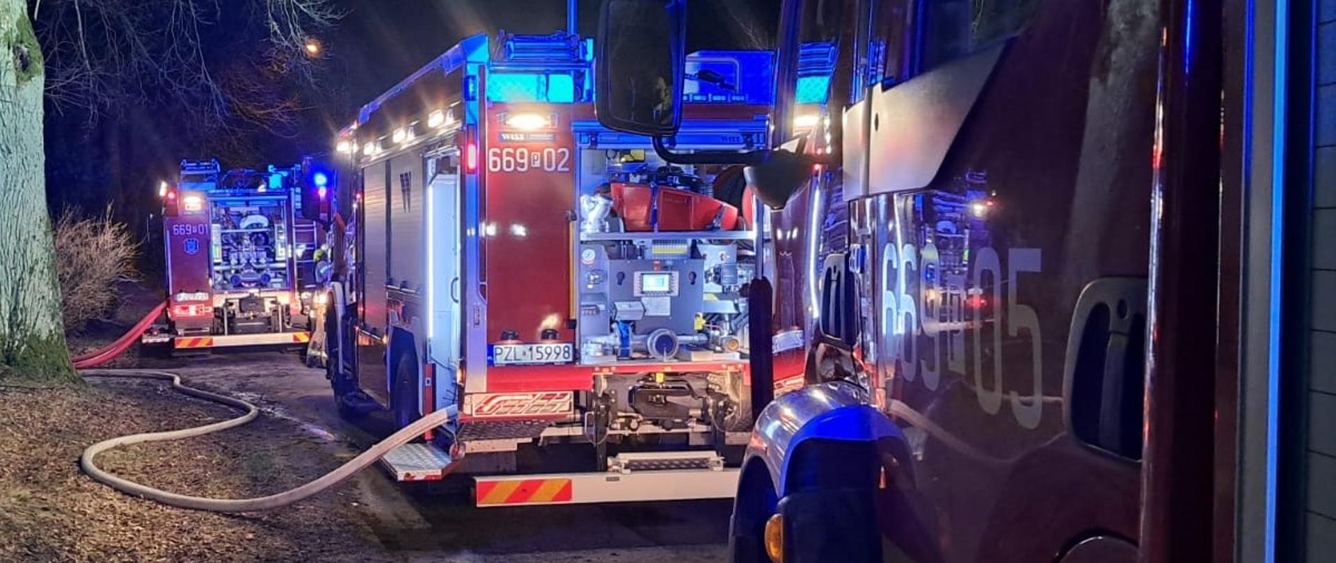 Strażackie samochody z włączonymi światłami alarmowymi droga gruntowa, noc