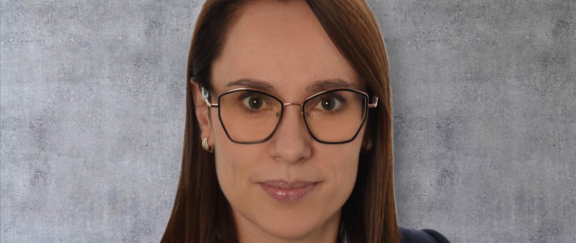 Zdjęcie przedstawia portret Pani Kierownik Wydziału Kontroli Justynę Magdziarz na marmurowym tle w okularach