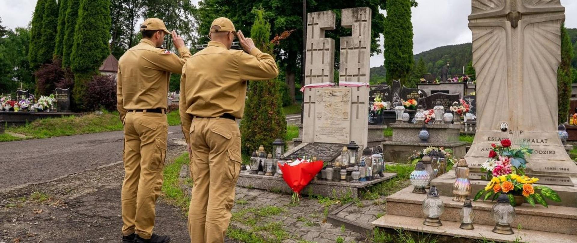 Zdjęcie przedstawia komendanta powiatowego i jego zastępce którzy oddają honor przy pomniku dla zamordowanych przez OUN i UPA.