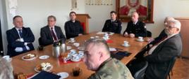 Zdjęcie przedstawia narade roczną w KP PSP Świdwin. Zaproszeni goście siedzą przy stole, oglądają prezentacje i słuchają Komendanta.