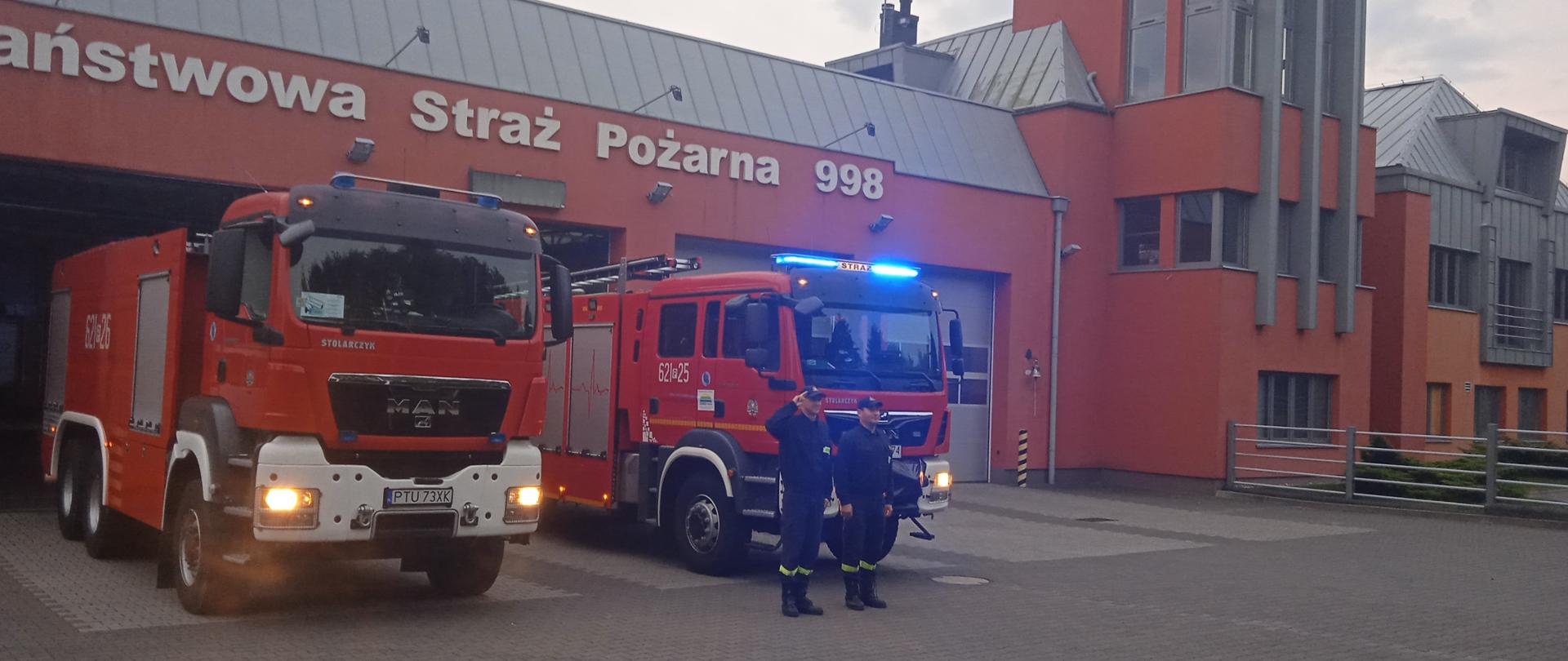 Strażacy oddający hołd zmarłemu strażakowi na tle pojazdów pożarniczych przed komenda KP PSP Turek.