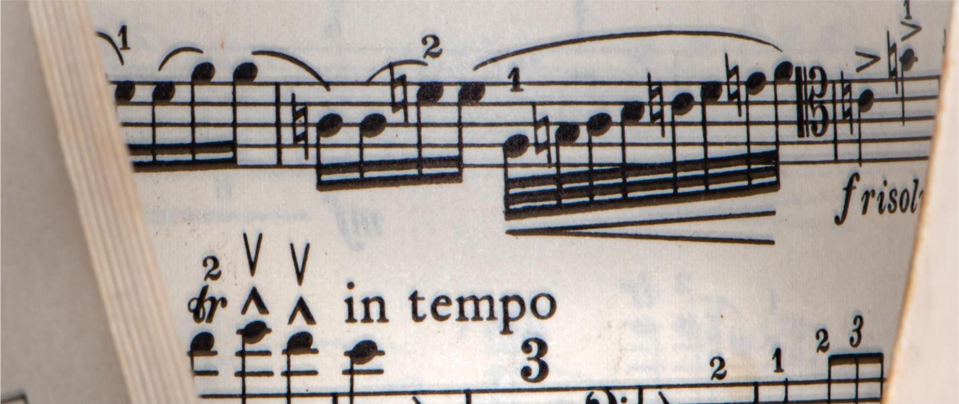 Grafika przedstawia zagięto kartkę z nutami