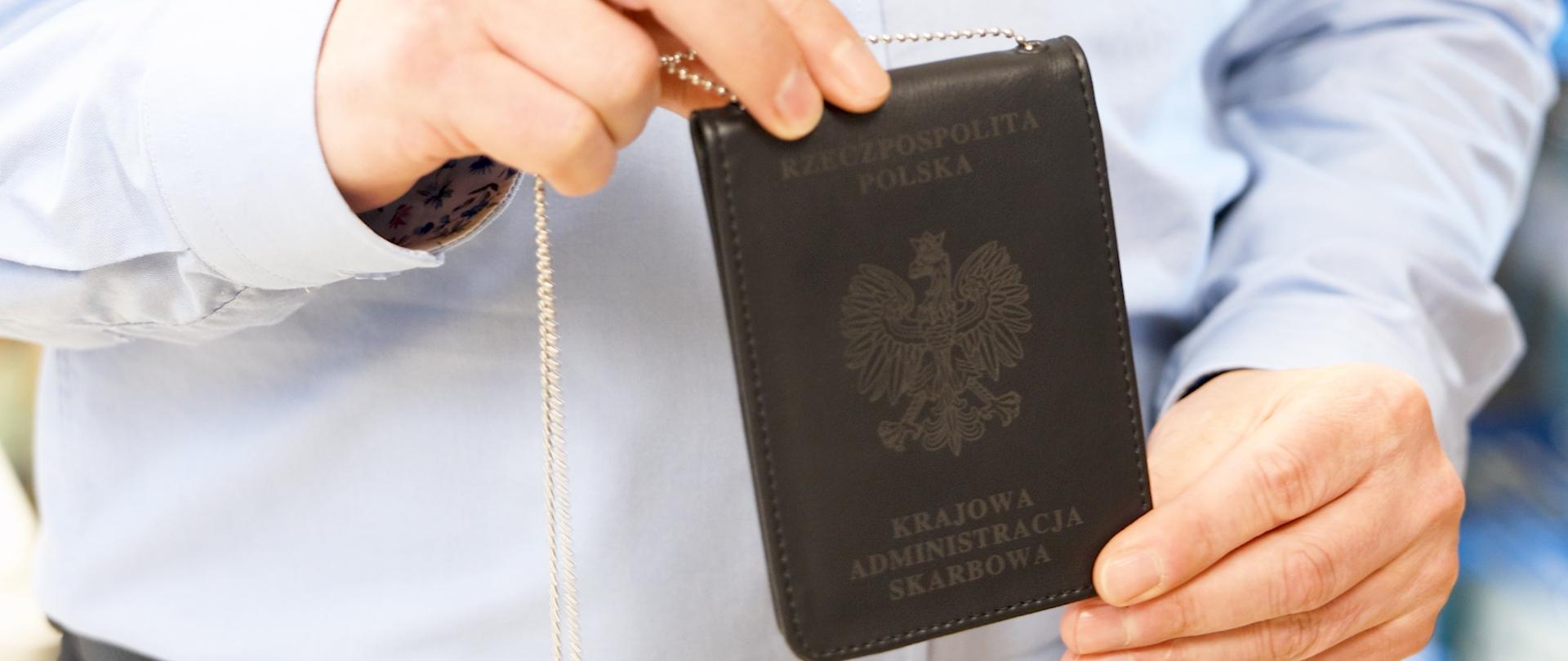Zdjęcie legitymacji służbowej pracownika KAS trzymanej w dłoniach